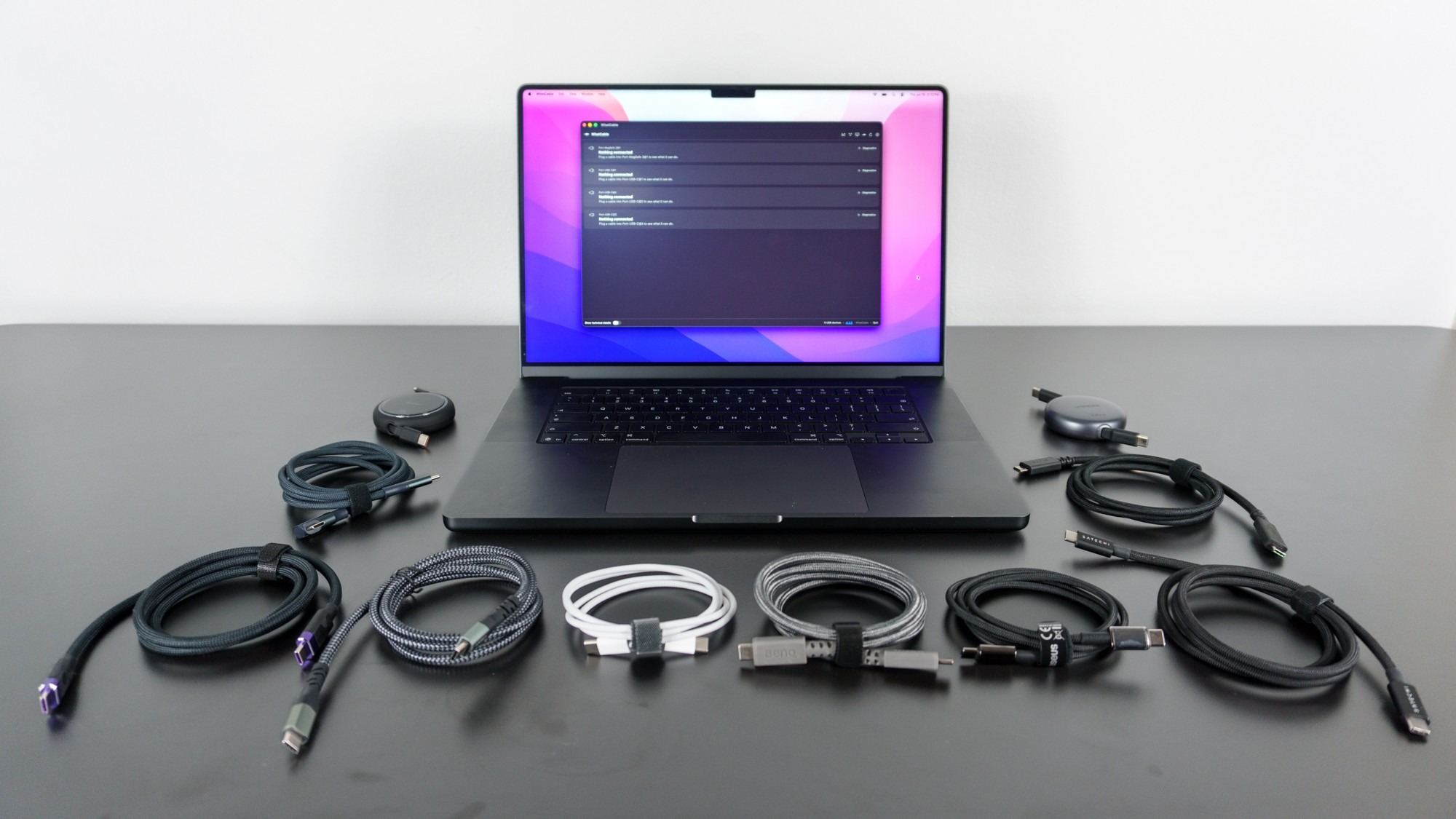 Several USB-C cables are arranged in front of a laptop running the cable-information app.